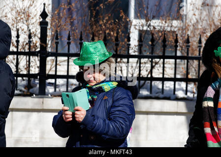 Eine ältere Frau trägt einen grünen Hut können Sie über Ihr Mobiltelefon in der Montreal St. Patrick's Day Parade Stockfoto