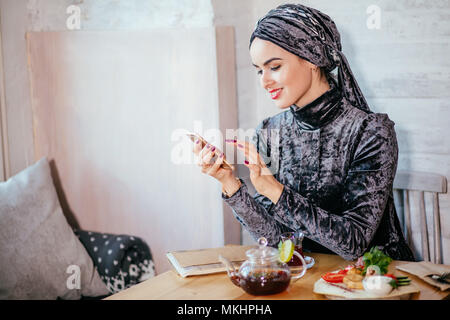 Moslemischen hijab Frauen Holding smartphonephone. SMS auf dem Telefon Stockfoto
