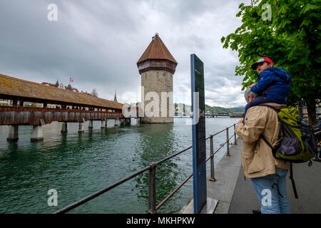 Kind sitzt auf den Schultern seines Großvaters neben der Kapellbrücke alias Kapellenbrücke in Luzerne, Schweiz, Europa Stockfoto