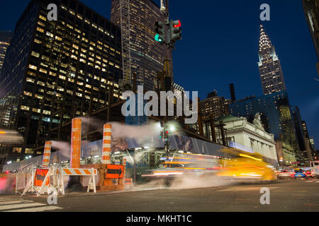 NEW YORK - USA - 31. Oktober 2017 - Lange Belichtung Foto des Autos über eine Kreuzung in New York City während der Dampf aus dem Schacht. Stockfoto