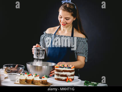 Frau Bäckerei Koch siebt Mehl, bereitet den Teig für Muffins. Stockfoto