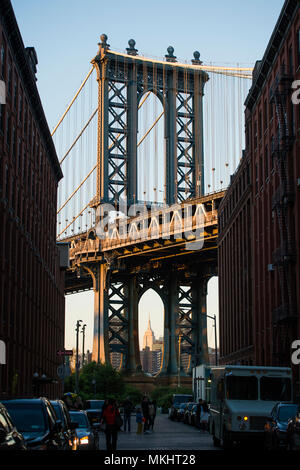 Brooklyn Bridge von einer engen Gasse, die von zwei Backstein Gebäude während des Sonnenuntergangs geschlossenen gesehen. New York City, USA. Stockfoto