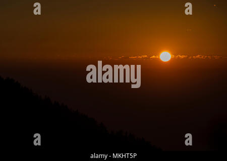 Sonnenuntergang hinter einem Berg mit der Silhouette von Bäumen, in Dharamsala, Indien. Stockfoto