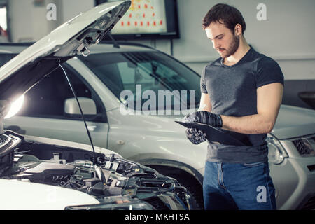 Konzentriert Mechaniker schreiben auf Zwischenablage in Werkstatt Stockfoto