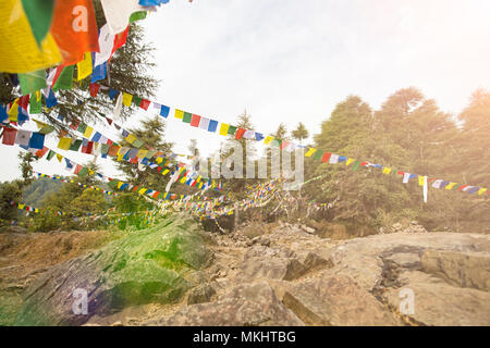 'Selektiven focus' Blick auf einige bunte tibetische Fahnen durch einen wunderschönen Sonnenuntergang auf dem Gipfel des Himalaya Mountain Forest beleuchtet Stockfoto