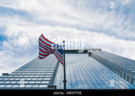 NEY YORK-USA - 28. Oktober 2017. Eine amerikanische Flagge weht auf ein unscharfes blaues Gebäude voll von Windows in Manhattan, New York, United States. Stockfoto