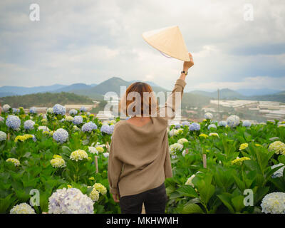 Vietnamesische Frau mit einem traditionellen Vietnam Hut in die Hortensie Blumen Garten Stockfoto