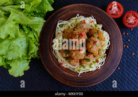 Nudeln (Spaghetti) mit Fleisch Bälle in einem Ton Schüssel auf einem dunklen Hintergrund. Die Ansicht von oben. Stockfoto