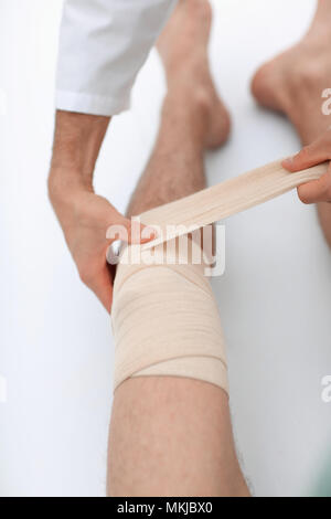 Closeup. Arzt bandagieren Bein des Patienten Stockfoto