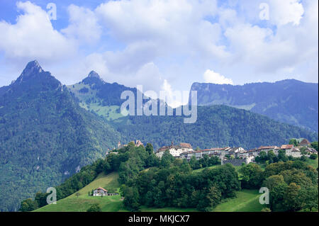 Panoramablick auf Gruyeres mittelalterliche Stadt in den Schweizer Alpen, Fribourg, Schweiz. Malerische Sommer Aussicht, grüne Hänge, Berge und bewölkter Himmel Stockfoto