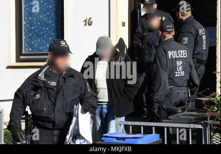 08 Mai 2018, Deutschland, Bremen: Polizisten festgenommen ein Mann aus einem Haus begleiten, ein Streifenwagen. Die deutsche Polizei hat eine groß angelegte Anti-menschenschmuggel Betrieb mit 800 Polizisten, die an Razzien in Wohnungen und Büros in Nord- und Mitteldeutschland. Der Grund für die Razzien wird die vermutete kommerzielle und Schleifring-basierten Handel mit Ausländern. Foto: Carmen Jaspersen/dpa - ACHTUNG: Individuelle(s) ist/sind verpixelt aus rechtlichen Gründen. Stockfoto