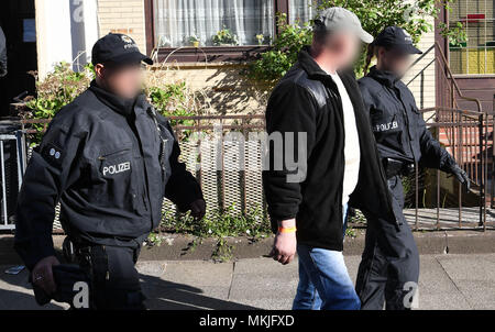 08 Mai 2018, Deutschland, Bremen: Polizisten festgenommen ein Mann aus einem Haus begleiten, ein Streifenwagen. Die deutsche Polizei hat eine groß angelegte Anti-menschenschmuggel Betrieb mit 800 Polizisten, die an Razzien in Wohnungen und Büros in Nord- und Mitteldeutschland. Der Grund für die Razzien wird die vermutete kommerzielle und Schleifring-basierten Handel mit Ausländern. Foto: Carmen Jaspersen/dpa - ACHTUNG: Individuelle(s) ist/sind verpixelt aus rechtlichen Gründen. Stockfoto