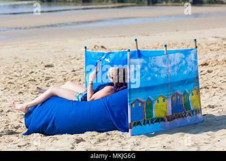 Bournemouth, Dorset, Großbritannien. 8. Mai 2018. UK Wetter: warmen und sonnigen Start in den Tag, eine junge Frau entspannt am Strand von Alum Chine Beach lesen Sie anzünden. Credit: Carolyn Jenkins/Alamy leben Nachrichten Stockfoto