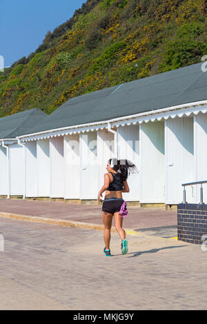 Bournemouth, Dorset, Großbritannien. 8. Mai 2018. UK Wetter: warmen und sonnigen Start in den Tag, als junge Frau joggt entlang der Promenade Vergangenheit Strandhütten. Credit: Carolyn Jenkins/Alamy leben Nachrichten Stockfoto