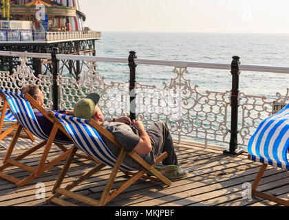 Brighton, East Sussex, 8. Mai 2018. Zwei Männer in Liegestühlen am Nachmittag Sonnenschein auf Brighton Pier entspannen. Ein weiteres schön sonnig und warm am Nachmittag in der Küstenstadt Brighton, East Sussex Mai haben die Letzten für eine Weile gewesen, als die Wettervorhersage ist kühler und trüber in den kommenden Tagen zu drehen. Credit: Imageplotter Nachrichten und Sport/Alamy leben Nachrichten Stockfoto