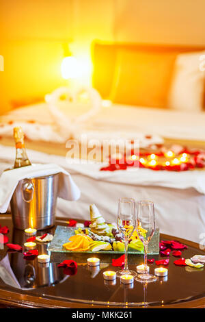 Romantisches Abendessen für Liebhaber: Tabelle mit einer Frucht Teller, Gläser Champagner, Sekt mit Eis in einer Metall Eimer und Kerzen, im Hintergrund ein. Stockfoto