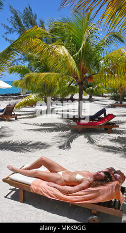 Sonnenbad unter Palmen am Strand im Hotel Hibiscus, Ort Pereybere, Nordwesten von Mauritius Stockfoto