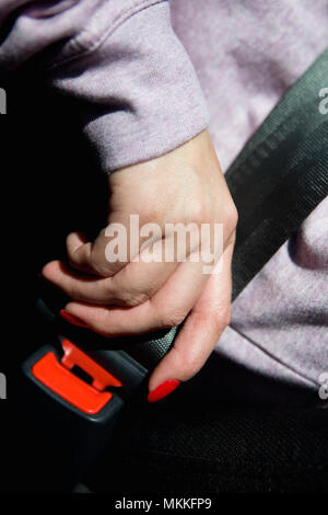 Die Hand einer Frau mit einem schönen Maniküre Befestigung des Sicherheitsgurts. Hinter dem Lenkrad. Stockfoto