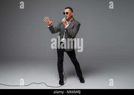 Das mittlere Alter Showman Interviewer mit Emotionen. Junge elegante reifer Mann mit Mikrofon gegen den weißen Hintergrund. Stockfoto