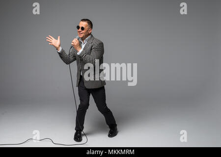 Das mittlere Alter Showman Interviewer mit Emotionen. Junge elegante reifer Mann mit Mikrofon gegen den weißen Hintergrund. Stockfoto