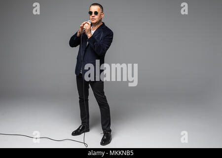 Das mittlere Alter Showman Interviewer mit Emotionen. Junge elegante reifer Mann mit Mikrofon gegen den weißen Hintergrund. Stockfoto