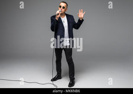 Das mittlere Alter Showman Interviewer mit Emotionen. Junge elegante reifer Mann mit Mikrofon gegen den weißen Hintergrund. Stockfoto