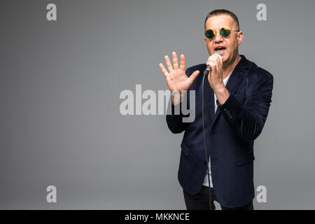 Das mittlere Alter Showman Interviewer mit Emotionen. Junge elegante reifer Mann mit Mikrofon gegen den weißen Hintergrund. Stockfoto