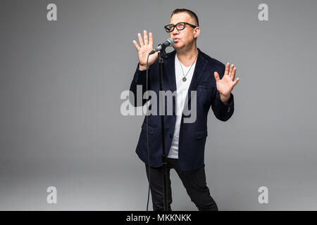Das mittlere Alter Showman Interviewer mit Emotionen. Junge elegante reifer Mann mit Mikrofon gegen den weißen Hintergrund. Stockfoto