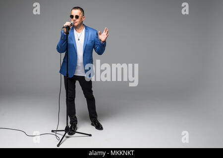 Das mittlere Alter Showman Interviewer mit Emotionen. Junge elegante reifer Mann mit Mikrofon gegen den weißen Hintergrund. Stockfoto