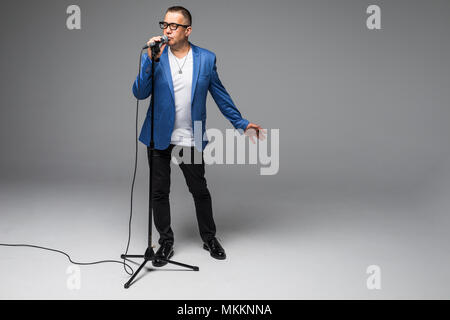 Das mittlere Alter Showman Interviewer mit Emotionen. Junge elegante reifer Mann mit Mikrofon gegen den weißen Hintergrund. Stockfoto