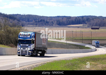 Angepasste super Scania Semi Truck von L Retva Oy hols Güter auf der Straße, mit Zusatzscheinwerfer leuchtet kurz auf. Ein weiteres Gerät der gleichen Firma folgt. Stockfoto