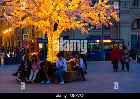 Moskau, Russland - 30 April, 2018: die Menschen ruhen auf Bänken in der Nähe des Roten Platzes. Dekorativer Künstlicher Baum mit LED-Beleuchtung. Am Abend vor Sonnenuntergang Stockfoto