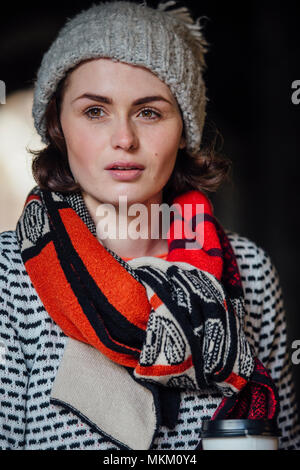 Winter Portrait von einer Frau mit einem Kaffee Tasse trägt einen Schal und Hut. Stockfoto