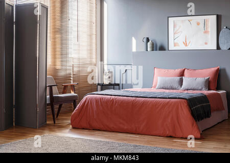 Echten Foto von eleganten Schlafzimmer Innenraum mit schwarzen Wänden, braunen Jalousien und orange Blätter auf grau Bed Stockfoto