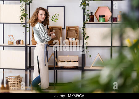 Lächelnde Verkäuferin Anordnen von natürlichen Gesundheitsprodukten auf Holzkisten im Shop Stockfoto