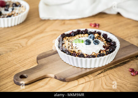 Close-up ein gesundes Frühstück mit Haferflocken und Rosinen mit Joghurt auf einem Holztisch Stockfoto