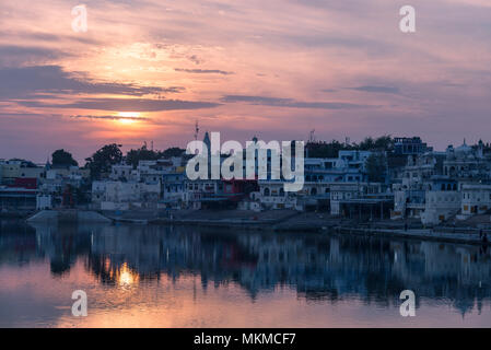 Bunte Himmel und Wolken über Pushkar, Rajasthan, Indien. Tempel, Gebäude und Farben auf das heilige Wasser der See bei Sonnenuntergang widerspiegelt. Stockfoto