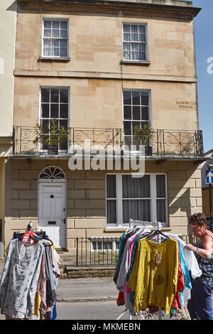 Frau auf der Suche nach Kleidung in Suffolk Markt mit einer Frist Regency House im Hintergrund, in der Nähe der Bath Road und Leckhampton, Cheltenham. Stockfoto