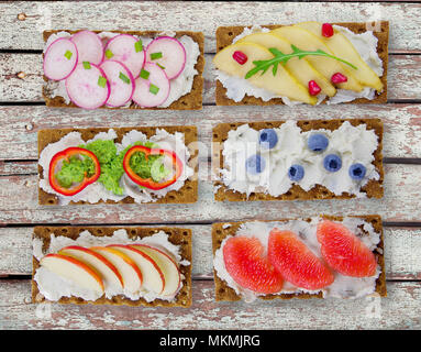 Sandwiches mit Frischkäse und frische Beeren, Früchte und Gemüse. Frische, gesunde Vorspeise Snack mit Knäckebrot. Stockfoto