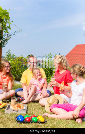 Familie mit Picknick im Garten vor dem Haus Stockfoto