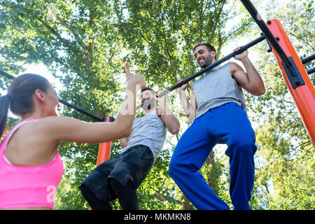 Zwei junge Männer sich wiederholende Pull-up-Übung während der Oberkörper Routine Stockfoto