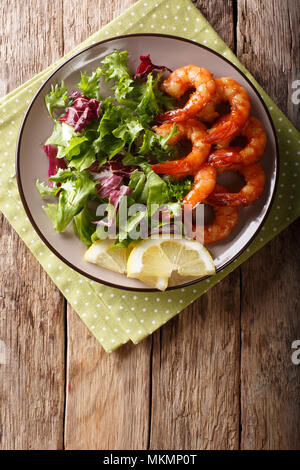 Köstlichen glasierten Garnelen mit Honig und Sojasauce und frischem Salat close-up auf einem Teller auf dem Tisch. Vertikal oben Ansicht von oben Stockfoto