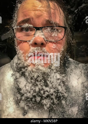 Mann mit Schnee und Eis auf seinem Gesicht und Bart, Island Stockfoto