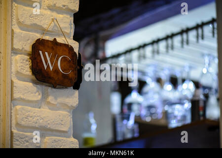 Schild an einer Wand mit einer Inschrift WC, vibrant Blue bokeh Stockfoto