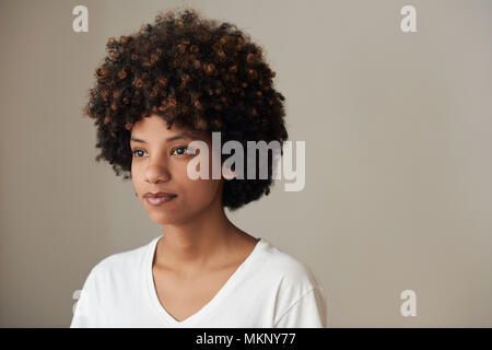 Serene suchen junge afrikanische Frau mit einem afro und natürlichen Teint, gegen einen grauen Hintergrund Stockfoto