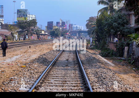 Menschen zu Fuß lässig auf den Schwellen der Gleisanlagen, in Indien. Wohnhäuser und Gewerbebetriebe grenzt an den Gleisen. Stockfoto