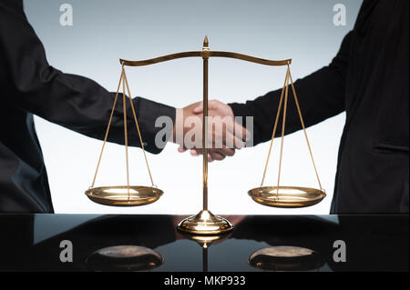 Nahaufnahme von Menschen die Hände schütteln vor der Waage Balance. Konzepte von Recht und Gerechtigkeit. Stockfoto