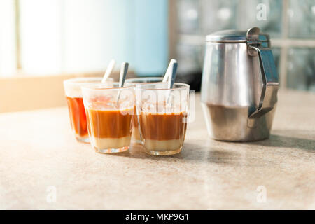 Gruppe von heißer Milch Kaffee in einem kleinen Glas mit einem Glas auf dem Tisch Stockfoto