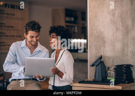 Inhaber kleiner Unternehmen mit Laptop in ihrem Restaurant. Das Lächeln des Mannes und der Frau in deren Restaurant zu arbeiten. Stockfoto