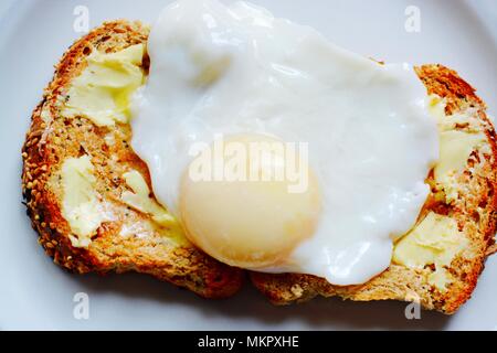 Die perfekt pochierte Eier auf Toast mit Butter braun mit Ausgangspunkten Stockfoto